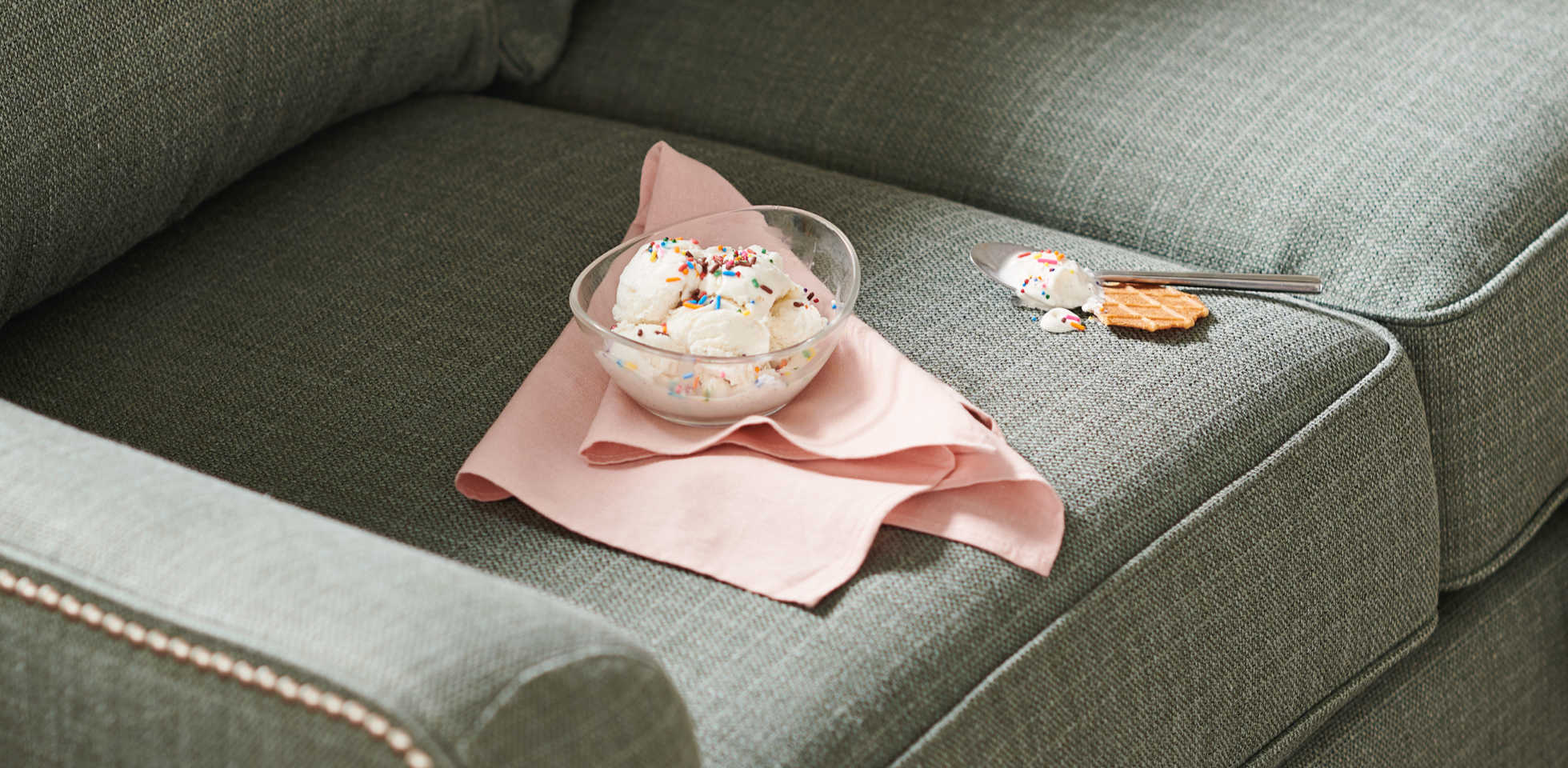 Bowl of ice cream on sofa with some spilled