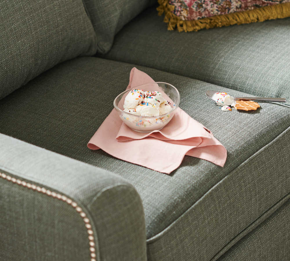 Bowl of ice cream on sofa with some spilled