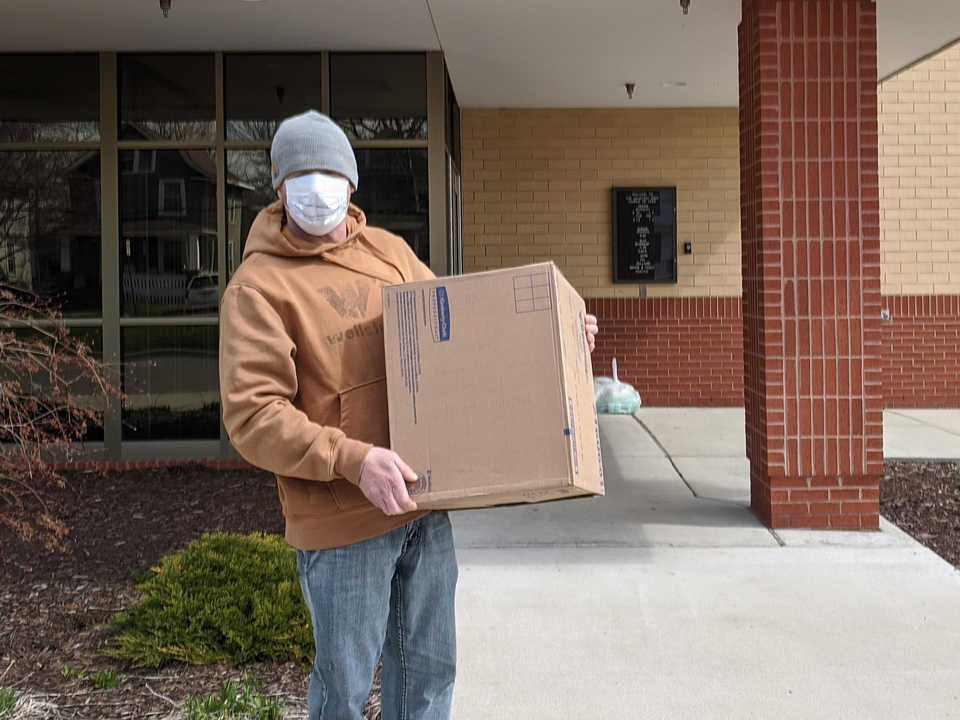 Worker with face mask carrying a box outside of Salvation Army