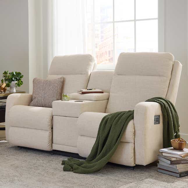 white fabric loveseat with a throw pillow and blanket sitting on it