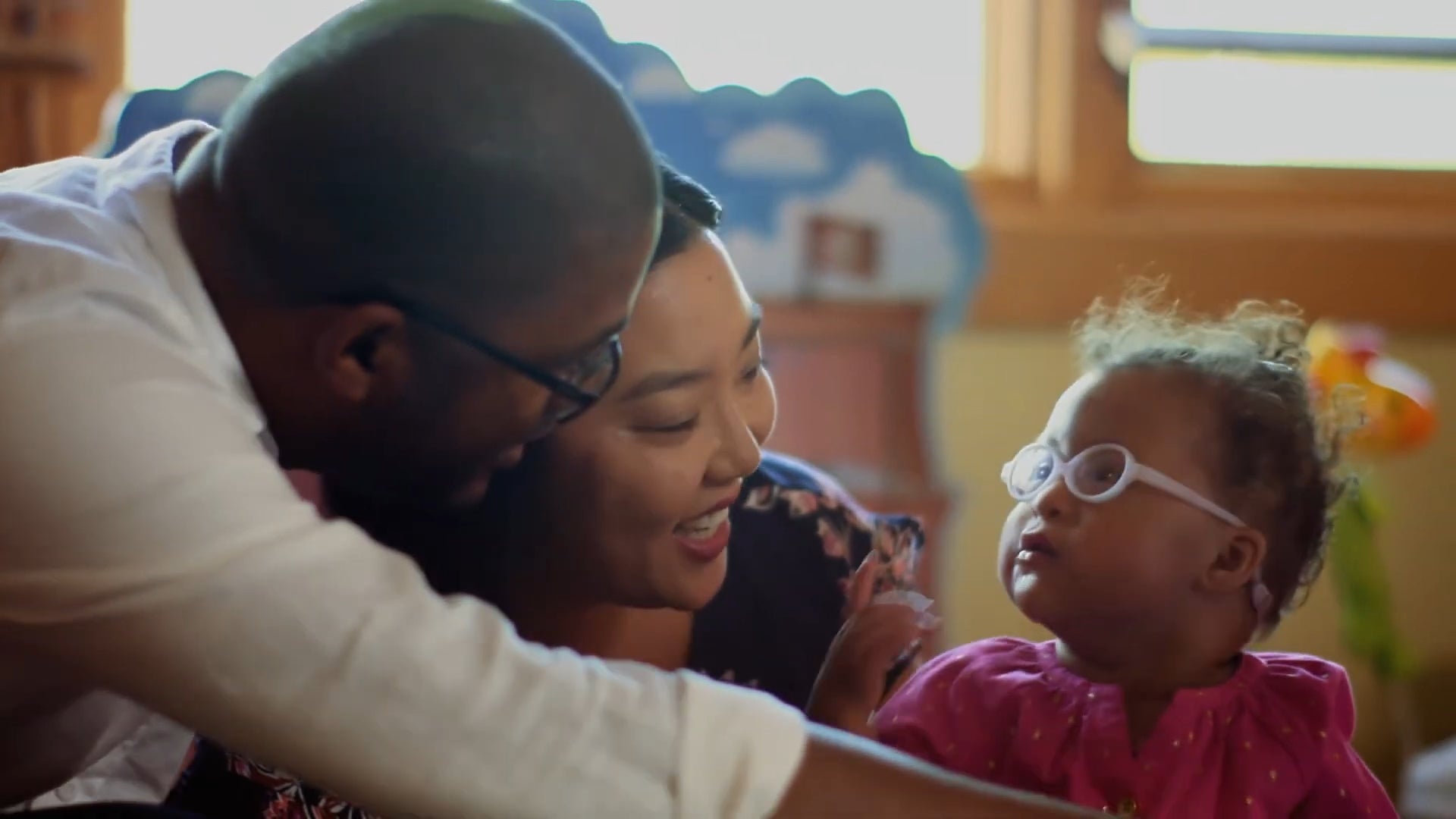 Smiling parents with a young child wearing glasses