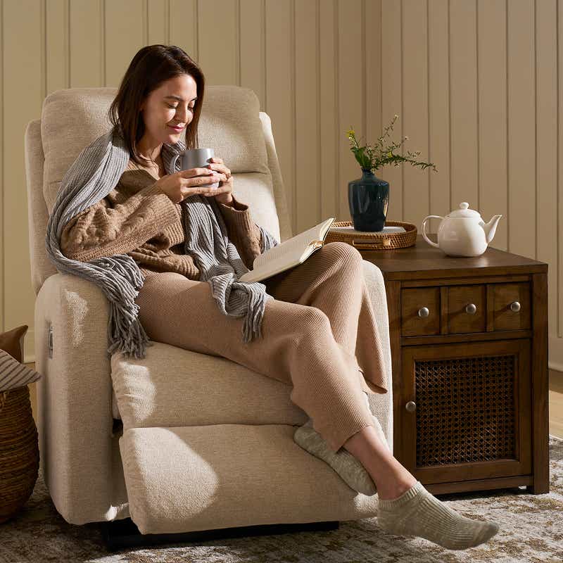 Une femme se relaxant dans un fauteuil inclinable lisant un livre