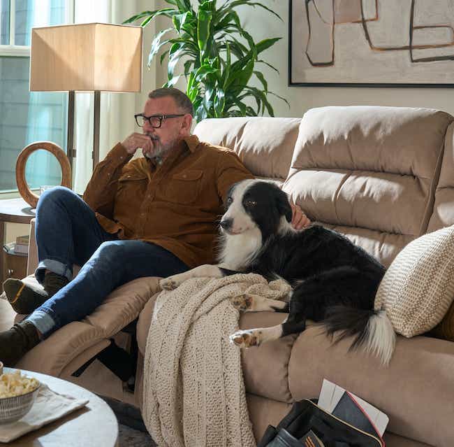 a man and a dog relaxing on a sofa